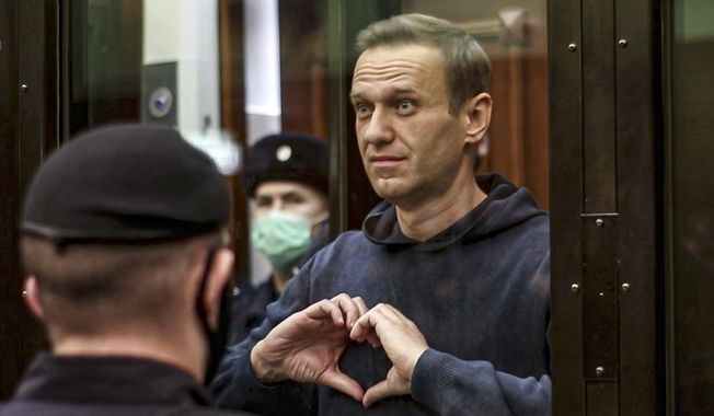 In this handout photo taken from video provided by the Moscow City Court on Feb. 2, 2021, Russian opposition leader Alexei Navalny shows a heart symbol while standing in a defendant’s cage during a hearing in the Moscow City Court in Moscow, Russia. Navalny, who died in an Arctic penal colony on Feb. 16, spent months in punishment cells for infractions like not buttoning his uniform properly or not putting his hands behind his back when required. (Moscow City Court via AP, File)