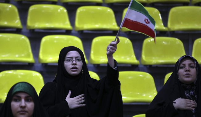 Iranian women listen to their country&#x27;s national anthem as one of them waves the national flag during an election campaign rally ahead of the March 1, parliamentary and Assembly of Experts elections, in Tehran, Iran, Tuesday, Feb. 27, 2024. Iran is holding parliamentary elections this Friday, yet the real question may not be who gets elected but how many people actually turn out to vote. Separately, Iranians will also vote on Friday for members of the country&#x27;s 88-seat Assembly of Experts, an eight-year term on a panel that will appoint the country&#x27;s next supreme leader after Khamenei, 84. (AP Photo/Vahid Salemi)