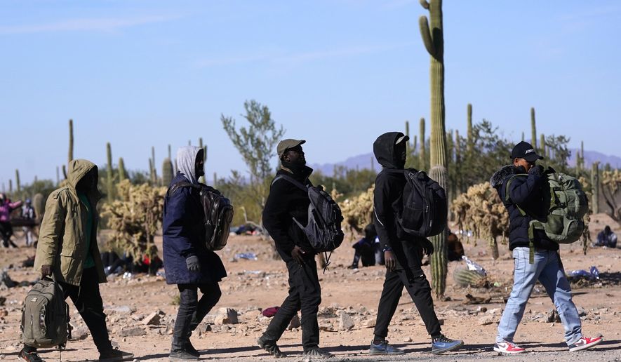 A group of migrants walk to a van as hundreds of migrants gather along the border Tuesday, Dec. 5, 2023, in Lukeville, Ariz. Republicans in swing state Arizona are doubling down on border security with legislation aimed at punishing migrants who enter the United States illegally, including one bill to lawfully allow property owners to shoot and kill anyone criminally trespassing on their property. Democratic Gov. Katie Hobbs is expected to veto both pieces of proposed legislation. AP Photo/Ross D. Franklin, File)