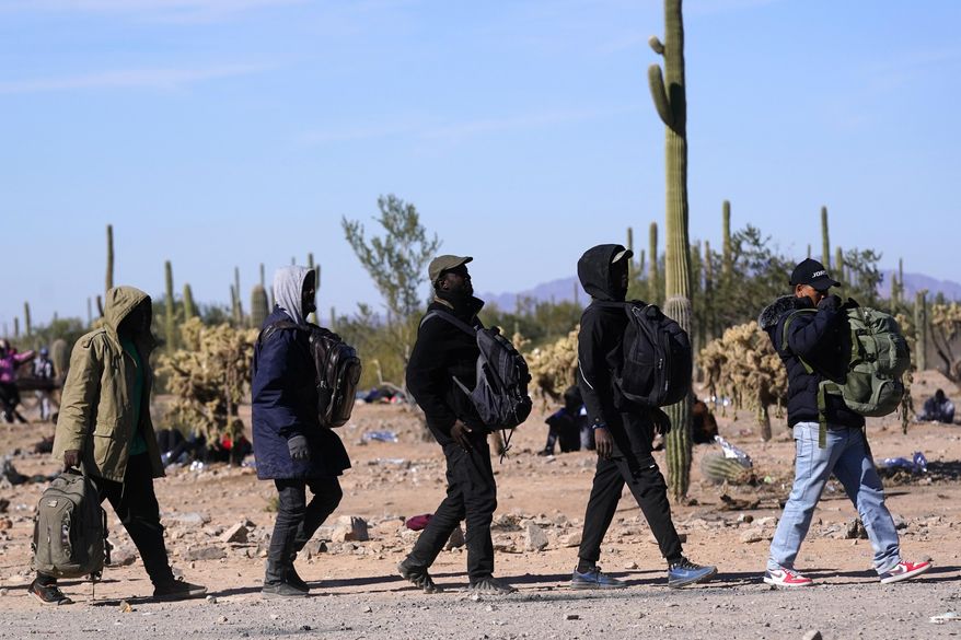 A group of migrants walk to a van as hundreds of migrants gather along the border Tuesday, Dec. 5, 2023, in Lukeville, Ariz. Republicans in swing state Arizona are doubling down on border security with legislation aimed at punishing migrants who enter the United States illegally, including one bill to lawfully allow property owners to shoot and kill anyone criminally trespassing on their property. Democratic Gov. Katie Hobbs is expected to veto both pieces of proposed legislation. AP Photo/Ross D. Franklin, File)