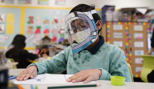 A student wears a mask and face shield in a 4th grade class amid the COVID-19 pandemic at Washington Elementary School on Jan. 12, 2022, in Lynwood, Calif. Four years after the COVID-19 pandemic closed schools and upended child care, the CDC says parents can start treating the virus like other respiratory illnesses. (AP Photo/Marcio Jose Sanchez, File)