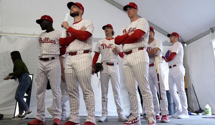Philadelphia Phillies players wait to have their photo taken during a baseball spring training photo day Thursday, Feb. 22, 2024, in Clearwater, Fla. Baseball players’ association head Tony Clark is hopeful 2024 uniforms will soon be altered following complaints by his members. The uniforms designed by Nike and manufactured by Fanatics have been criticized by players for pants that are somewhat see through and for lettering, sleeve emblems and numbering that are less bulky and apparently smaller.(AP Photo/Charlie Neibergall, File)