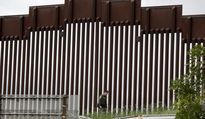 A Border Patrol agent walks along a border wall separating Tijuana, Mexico, from San Diego, in San Diego, on March 18, 2020. Eleven people were found hurt Saturday, March 2, 2024, after trying to climb over a wall that separates Mexico and the United States and falling on the San Diego side, the latest such injuries since the wall was heightened to deter illegal crossings. (AP Photo/Gregory Bull, File)