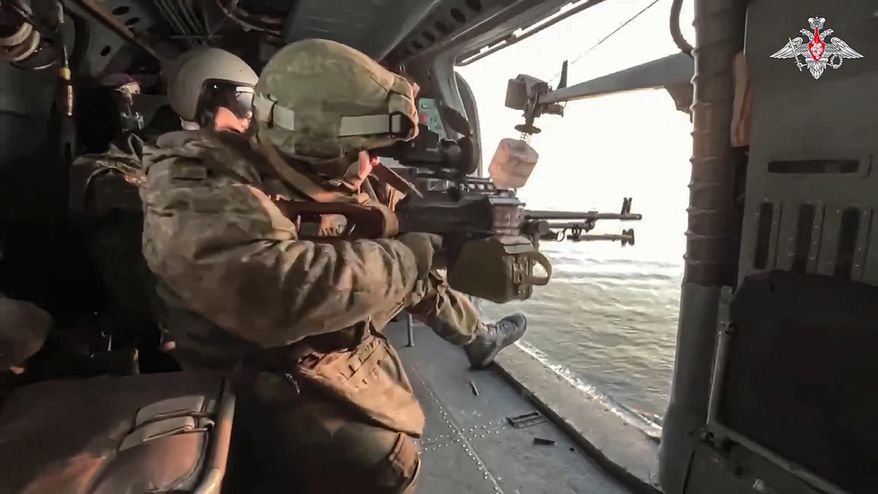 In this photo taken from video released by the Russian Defense Ministry Press Service on Jan. 5, 2024, Russian soldiers fire from aboard a Ka-27 helicopter of the Russian Black Sea Fleet during a patrol of the Black Sea. (Russian Defense Ministry Press Service via AP, File)