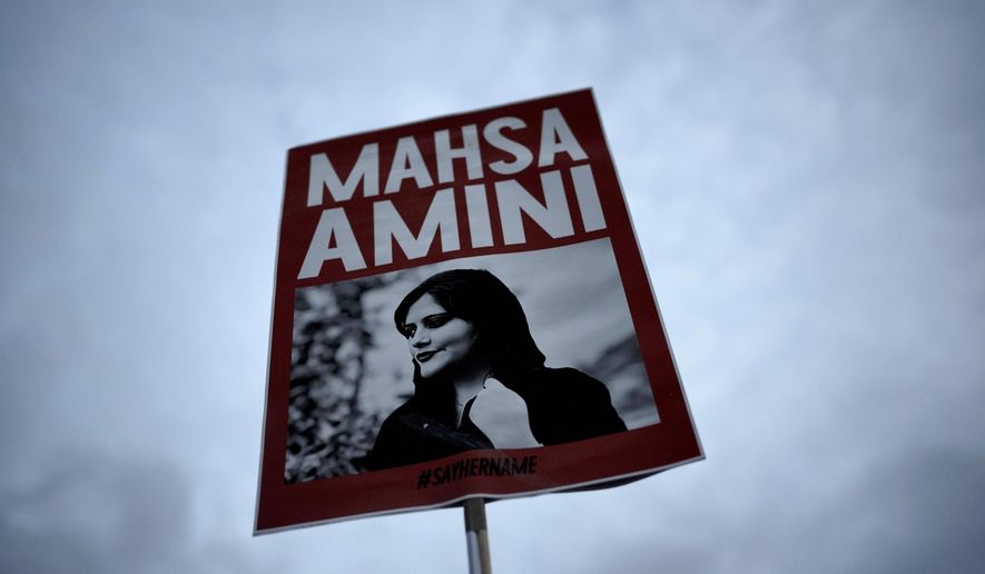 FILE - A woman holds a placard with a picture of Iranian woman Mahsa Amini during a protest against her death, in Berlin, Germany, on Sept. 28, 2022. Iran is responsible for the "physical violence" that led to the death of Mahsa Amini in September 2022 and sparked nationwide protests against the country's mandatory headscarf, or hijab, laws and its ruling theocracy, a U.N. fact-finding mission said Friday, March 8, 2024. (AP Photo/Markus Schreiber, File)