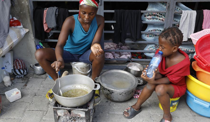 A woman cooks at shelter for families displaced by gang violence, in Port-au-Prince, Haiti, Friday, March 8, 2024. The violence as anti-government gangs battle police in the streets has crippled Haiti’s economy and made it extremely difficult for many of the country's most vulnerable to feed themselves.(AP Photo/Odelyn Joseph)