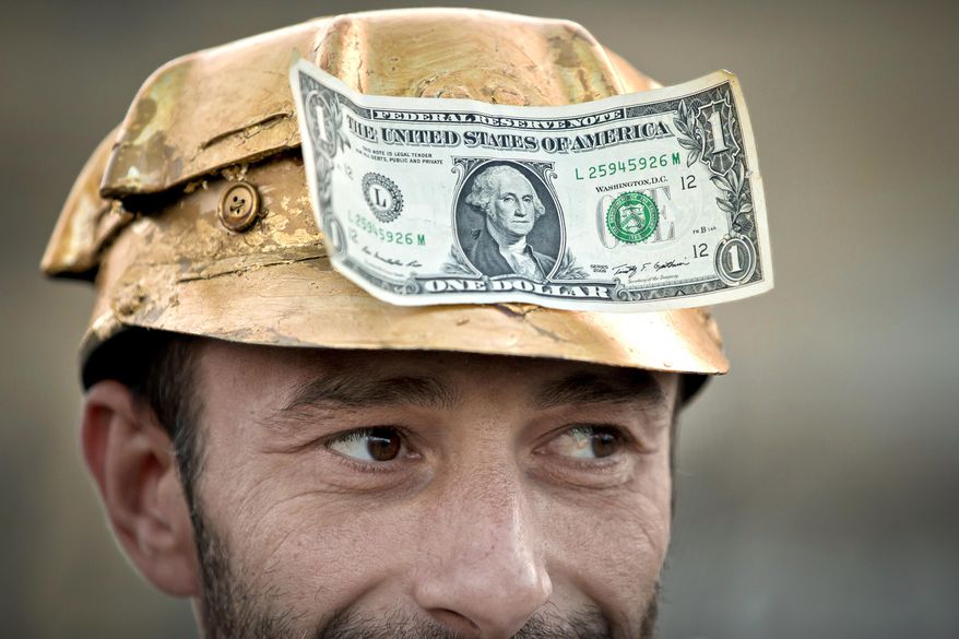 A man wears a one dollar bill on a miner's helmet painted in gold color in Bucharest, Romania, Sept. 21, 2013, during a protest against the exploitation of gold by by Gabriel Resources, a Canadian mining company, at Rosia Montana, the site of ancient Roman mining galleries in a mountainous western Romanian region and home to Europe's largest gold deposits. The Romanian government has won a years-long legal dispute with a Canadian mining company seeking financial damages over failed plans to open a gold and silver mine in the Eastern European country. (AP Photo/Vadim Ghirda, File)