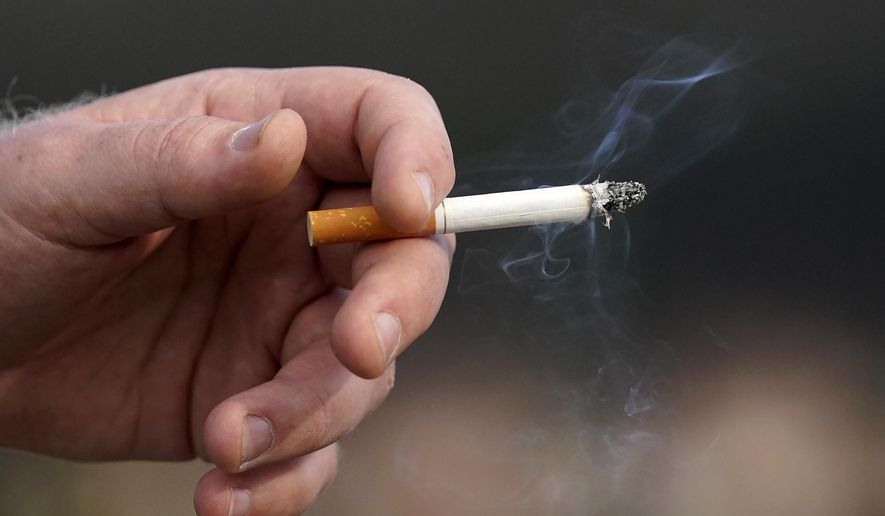 A man holds a lit cigarette while smoking, Dec. 2, 2020, in San Francisco. Brookline, Mass., has adopted an unusual smoking ban that bars tobacco sales to anyone born in the 21st century. The bylaw — the first of its kind in the country — was adopted by Brookline in 2020 and on Friday, March 8, 2024, was upheld by the state’s highest court, opening the door for other communities to adopt similar bans that will, decades from now, eventually ban all future generations from buying tobacco. (AP Photo/Jeff Chiu, File)