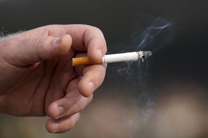 A man holds a lit cigarette while smoking, Dec. 2, 2020, in San Francisco. Brookline, Mass., has adopted an unusual smoking ban that bars tobacco sales to anyone born in the 21st century. The bylaw — the first of its kind in the country — was adopted by Brookline in 2020 and on Friday, March 8, 2024, was upheld by the state’s highest court, opening the door for other communities to adopt similar bans that will, decades from now, eventually ban all future generations from buying tobacco. (AP Photo/Jeff Chiu, File)