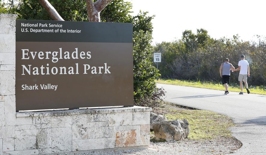 Visitors walk past a sign for Everglades National Park as they enter from overflow parking, Wednesday, Jan. 2, 2019, in Everglades National Park, Fla. Officials say a man visiting the Florida Everglades is recovering after being bitten by a crocodile after falling off a boat. The National Park Service says the attack occurred Sunday, March 10, 2024 at the Flamingo Marina in Everglades National Park. (AP Photo/Wilfredo Lee)