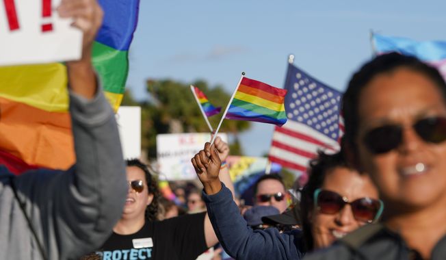 Marchers wave U.S. and rainbow flags and signs as they walk at the St. Pete Pier in St. Petersburg, Fla., on Saturday, March 12, 2022, during a rally and march to protest what critics call the &quot;Don&#x27;t say gay&quot; bill passed by Florida&#x27;s Republican-led Legislature and now on its way to Gov. Ron DeSantis&#x27; desk. (Martha Asencio-Rhine/Tampa Bay Times via AP, File)