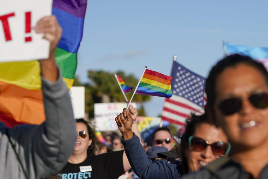 Marchers wave U.S. and rainbow flags and signs as they walk at the St. Pete Pier in St. Petersburg, Fla., on Saturday, March 12, 2022, during a rally and march to protest what critics call the "Don't say gay" bill passed by Florida's Republican-led Legislature and now on its way to Gov. Ron DeSantis' desk. (Martha Asencio-Rhine/Tampa Bay Times via AP, File)