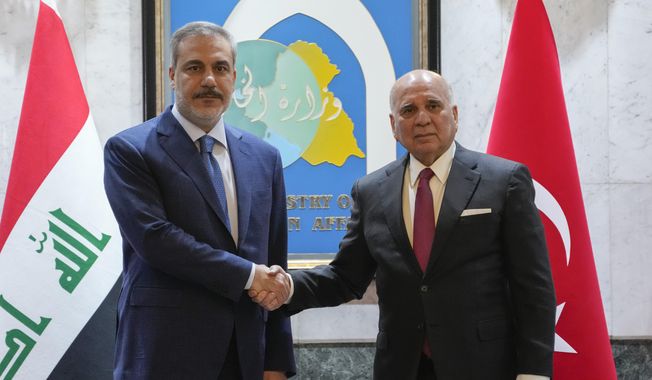Iraqi Foreign Minister Fouad Hussein, right, shakes hands with visiting Turkish Foreign Affairs Minister Hakan Fidan in Baghdad, Iraq, Thursday, March 14, 2024. (AP Photo/Hadi Mizban)