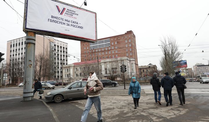 Pedestrians walk past a billboard which promotes the upcoming presidential election with words in Russian: &quot;Together we are strong, we vote for Russia!&quot; in a street in Donetsk, the capital of Russian-controlled Donetsk region, eastern Ukraine, on Thursday, March 14, 2024. Russian President Vladimir Putin Thursday called on people in Ukraine&#x27;s occupied regions to vote, telling them and Russians that participation in the elections is &quot;manifestation of patriotic feeling,&quot; Presidential elections are scheduled in Russia for March 17. (AP Photo)