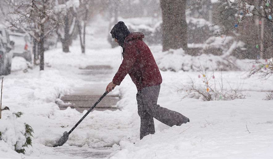A homeowner clears snow from a walkway as a late winter storm regained strength and resumed snowing Thursday, March 14, 2024, in Denver. Forecasters predict that the storm, which has already dropped a foot or more of snow on the region, will persist until early Friday, snarling traffic along Colorado&#x27;s Front Range communities. (AP Photo/David Zalubowski)