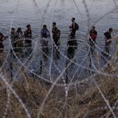 Migrants wait to climb over concertina wire after they crossed the Rio Grande and entered the U.S. from Mexico, Sept. 23, 2023, in Eagle Pass, Texas. A divided Supreme Court on Tuesday, March 19, 2024, lifted a stay on a Texas law that gives police broad powers to arrest migrants suspected of crossing the border illegally, while a legal battle over immigration authority plays out. (AP Photo/Eric Gay) **FILE**