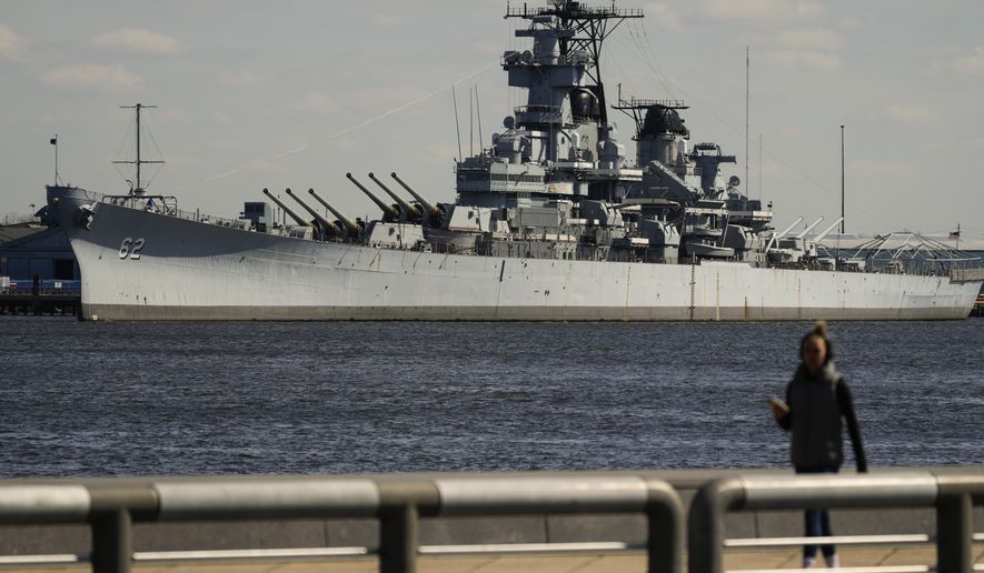 A person walks in Philadelphia across the Delaware River from the USS New Jersey in Camden, N.J., Tuesday, March 19, 2024. The battleship is scheduled to move from its dock in Camden on March 21, when it will head to the Philadelphia Navy Yard for extensive maintenance work. The USS New Jersey is scheduled to move from its dock in Camden on Thursday, March 21, 2024, when it will head to the Philadelphia Navy Yard for extensive maintenance work. (AP Photo/Matt Rourke)