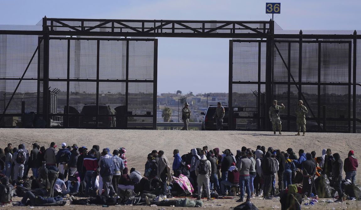 Migrants who crossed the border from Mexico into the U.S. wait next to the U.S. border wall where U.S. Border Patrol agents stand guard, seen from Ciudad Juarez, Mexico, March 30, 2023. (AP Photo/Fernando Llano, File)