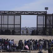 Migrants who crossed the border from Mexico into the U.S. wait next to the U.S. border wall where U.S. Border Patrol agents stand guard, seen from Ciudad Juarez, Mexico, March 30, 2023. (AP Photo/Fernando Llano, File)