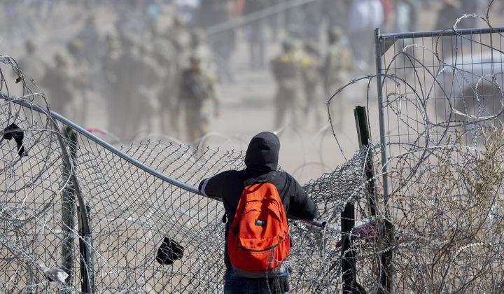 A migrant observes migrants who breached the concertina wire on the Rio Grande in El Paso, Texas on Thursday, March 21, 2024. The migrants were hoping to be processed by Border Patrol. (Omar Ornelas/El Paso Times via AP)