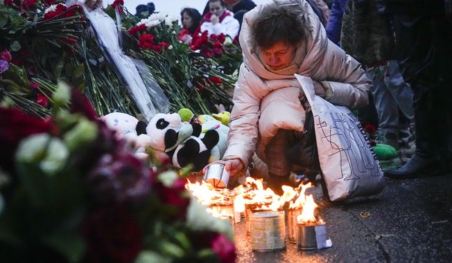 A woman lights candles at the fence next to the Crocus City Hall, on the western edge of Moscow, Russia, Saturday, March 23, 2024. Russia&#x27;s top state investigative agency says the death toll in the Moscow concert hall attack has risen to over 133. The attack Friday on Crocus City Hall, a sprawling mall and concert venue on Moscow&#x27;s western edge, also left many wounded and left the building a smoldering ruin. (AP Photo/Alexander Zemlianichenko)