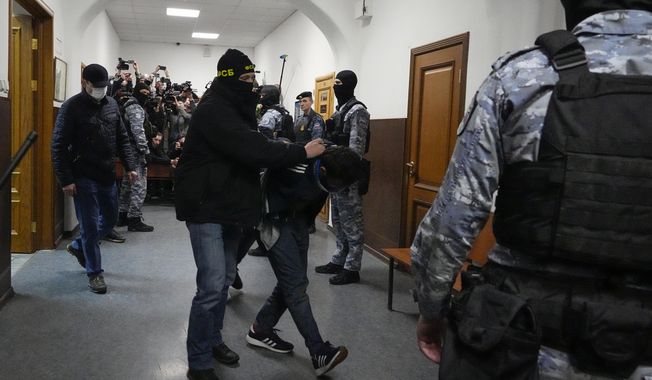 A suspect in the Crocus City Hall shooting on Friday, is escorted by police officers in the Basmanny District Court in Moscow, Russia, Sunday, March 24, 2024. (AP Photo/Alexander Zemlianichenko)