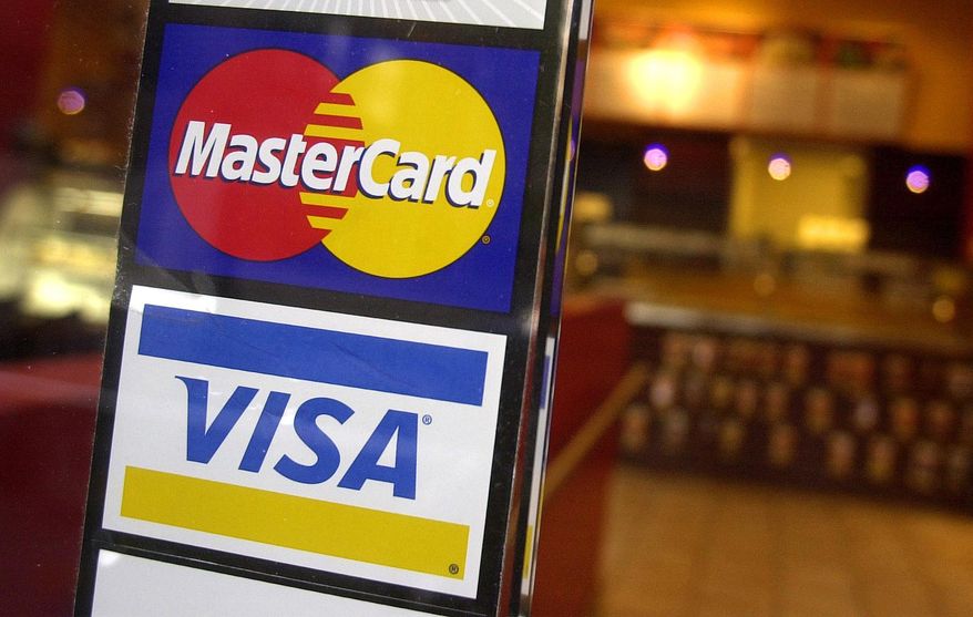 This April 22, 2005, file photo shows logos for MasterCard and Visa credit cards at the entrance of a New York coffee shop. (AP Photo/Mark Lennihan, File)