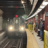 Subway riders stand near yellow barriers on a platform of the 7 train in New York on Tuesday, March 26, 2024. The city is experimenting with barriers to improve safety. (AP Photo/Cedar Attanasio)