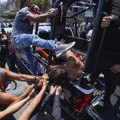 A woman suspected in the kidnapping and killing of an 8-year-old girl, is dragged out of a police vehicle by a mob in Taxco, Mexico, Thursday, March 28, 2024. (AP Photo/Fernando Llano)