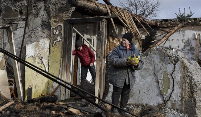 Inna, 71, holds food items found as she stands outside her house which was destroyed by a Russian drone attack in a residential neighborhood, in Zaporizhzhia, Ukraine, on Thursday, March 28, 2024. (AP Photo/Andriy Andriyenko)