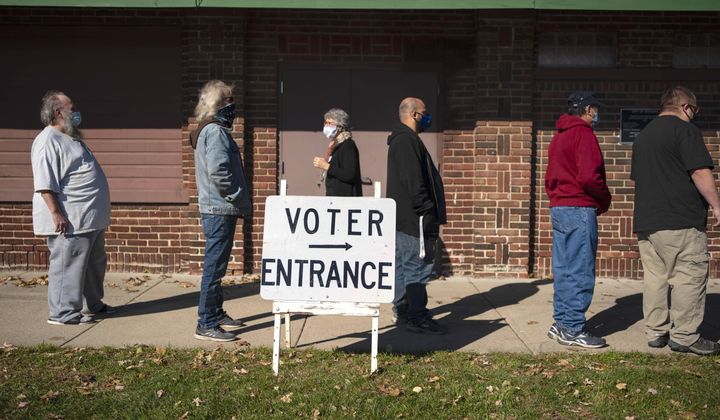 In this Nov. 3, 2020, file photo, voters wait in line outside a polling center on Election Day, in Kenosha, Wis. U.S. voters went to the polls starkly divided on how they see President Donald Trump’s response to the coronavirus pandemic. But in places where the virus is most rampant now, Trump enjoyed enormous support. (AP Photo/Wong Maye-E, File)