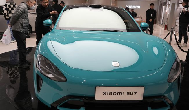 Visitors to the Xiaomi Automobile flagship store look at the Xiaomi SU7 electric car on display in Beijing, Tuesday, March 26, 2024. Xiaomi, a well-known smart consumer electronics brand in China, is joining the country&#x27;s booming but crowded market for electric cars. (AP Photo/Ng Han Guan)