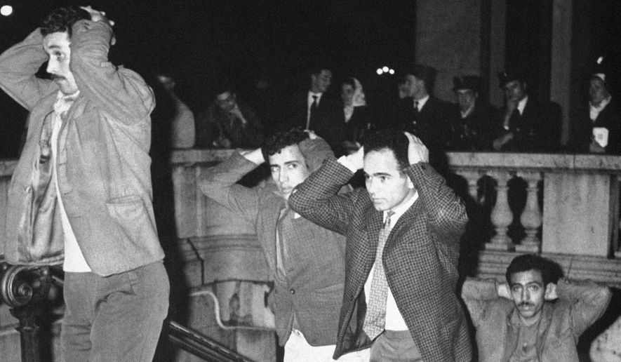 Men come out of the Paris subway station with their hands on their heads after being arrested in Paris, on Oct. 17, 1961, for failure to obey the curfew imposed on Algerians. Algerians and wounding at least four. French lawmakers on Thursday, March 28, 2024, condemned an infamous 1961 police crackdown on Algerian protesters in Paris as a &quot;bloody and murderous repression,&quot; marking another step in the country&#x27;s recognition of the massacre that authorities sought to cover up for decades. (AP Photo, File)