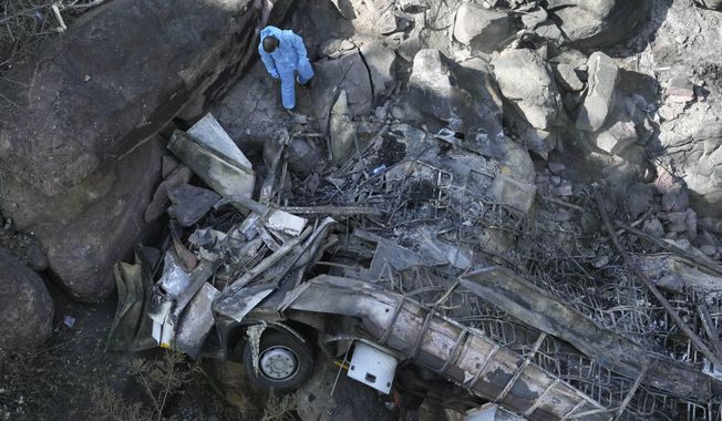 The wreckage of a bus lays in a ravine a day after it plunged off a bridge on the Mmamatlakala mountain pass between Mokopane and Marken, around 300km (190 miles) north of Johannesburg, South Africa, Friday, March 29, 2024. The bus carrying worshippers on a long-distance trip from Botswana to an Easter weekend church gathering in South Africa plunged off a bridge on a mountain pass Thursday and burst into flames as it hit the rocky ground below, killing at least 45 people, authorities said. The only survivor was an 8-year-old child who was receiving medical attention for serious injuries. (AP Photo/Themba Hadebe)