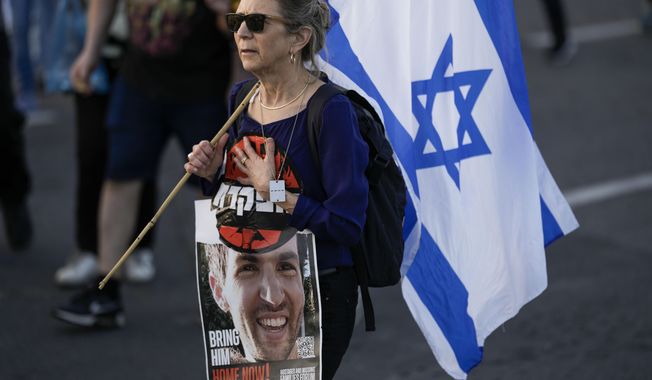A woman walks during a protest against Israeli Prime Minister Benjamin Netanyahu&#x27;s government and call for the release of hostages held in the Gaza Strip by the Hamas militant group outside of the Knesset, Israel&#x27;s parliament, in Jerusalem, Sunday, March 31, 2024. Tens of thousands of Israelis gathered outside the parliament building in Jerusalem on Sunday, calling on the government to reach a deal to free dozens of hostages held by Hamas and to hold early elections. (AP Photo/Leo Correa)