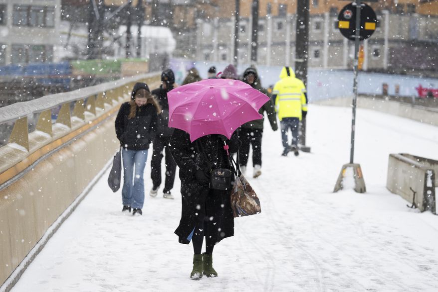 Pedestrians make their way through the snowy weather in Stockholm, Sweden April 2, 2024. Winter is not yet over in southern Sweden, spring took a break after a few Easter days with higher temperatures. (Anders Wiklund/TT via AP)