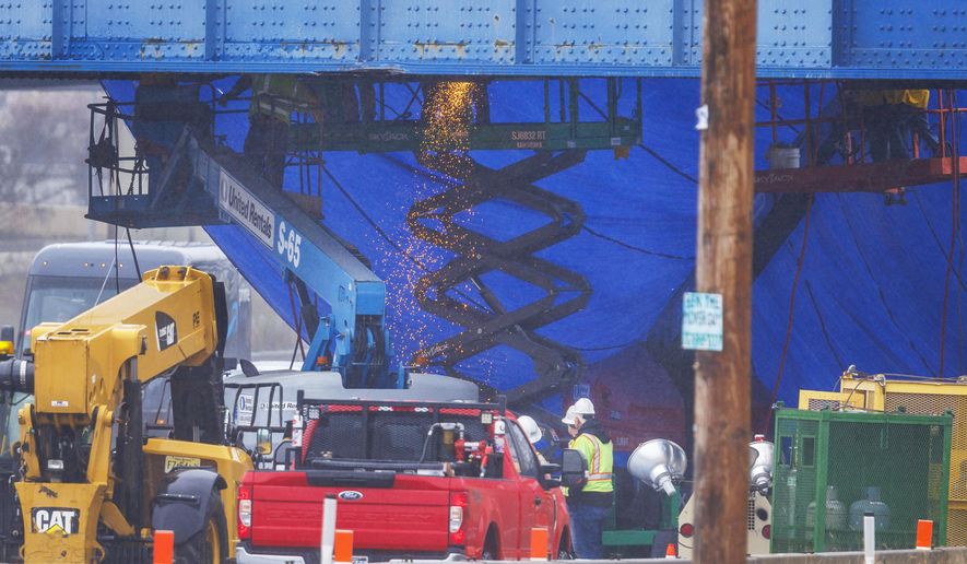 Work crews attend to a damaged railroad bridge over the I-95 interstate highway in Philadelphia, on Tuesday morning, April, 2, 2024. A truck collided with the bridge on Monday forcing the closure of I95. (Alejandro A. Alvarez/The Philadelphia Inquirer via AP)