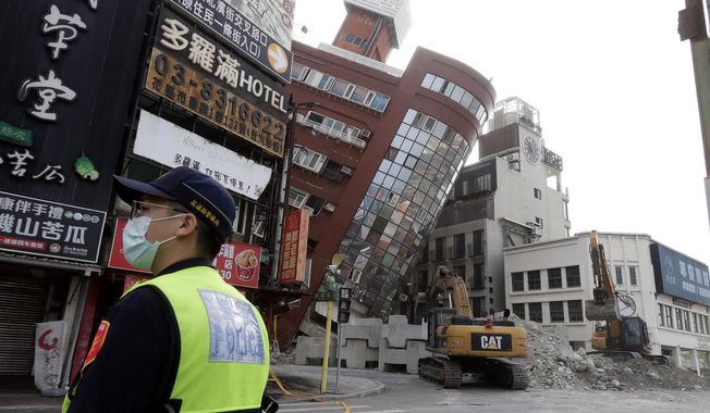 A police officer stands guard near a partially collapsed building a day after a powerful earthquake struck in Hualien City, eastern Taiwan, Thursday, April 4, 2024. (AP Photo/Chiang Ying-ying)