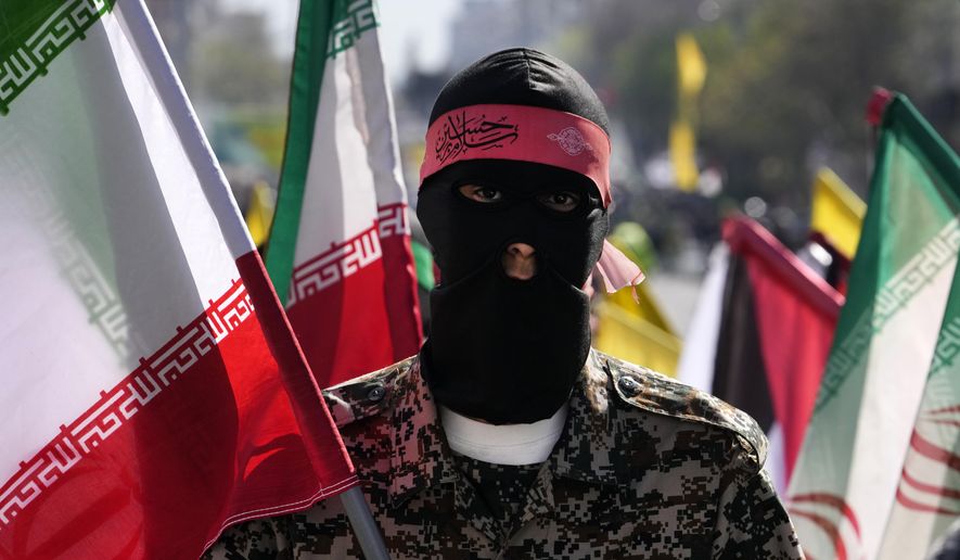 A member of the Iranian paramilitary Basij force holds an Iranian flag as he covers his face in the Palestinian and Lebanese militants style in an annual rally to mark Quds Day, or Jerusalem Day, to support the Palestinians in Tehran, Iran, Friday, April 5, 2024. In the rally in Tehran, thousands attended a funeral procession for the seven Revolutionary Guard members killed in an airstrike widely attributed to Israel that destroyed Iran&#x27;s Consulate in the Syrian capital on Monday. (AP Photo/Vahid Salemi)
