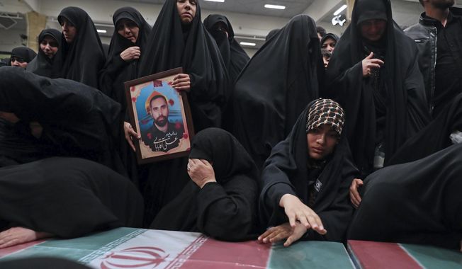 In this photo released by an official website of the office of the Iranian supreme leader, families mourn over the flag-draped coffins of the Iranian Revolutionary Guards members who were killed in an airstrike in Syria on Monday widely blamed on Israel, in Tehran, Iran, Thursday, April 4, 2024. (Office of the Iranian Supreme Leader via AP)