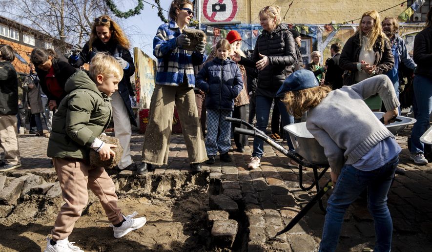 Citizens of the free village Christiania jointly dig up the cobblestones at Pusher Street, in Copenhagen, Denmark, Saturday April 6, 2024. After the cobblestones are removed, new water pipes and a new pavement will be laid on Pusher Street and nearby buildings will be renovated. That is the first step in an overall plan to turn the hippie oasis into an integrated part of the Danish capital area, although “the free state&quot; spirit of creativity and community life is to be maintained. (Ida Marie Odgaard/Ritzau Scanpix via AP)