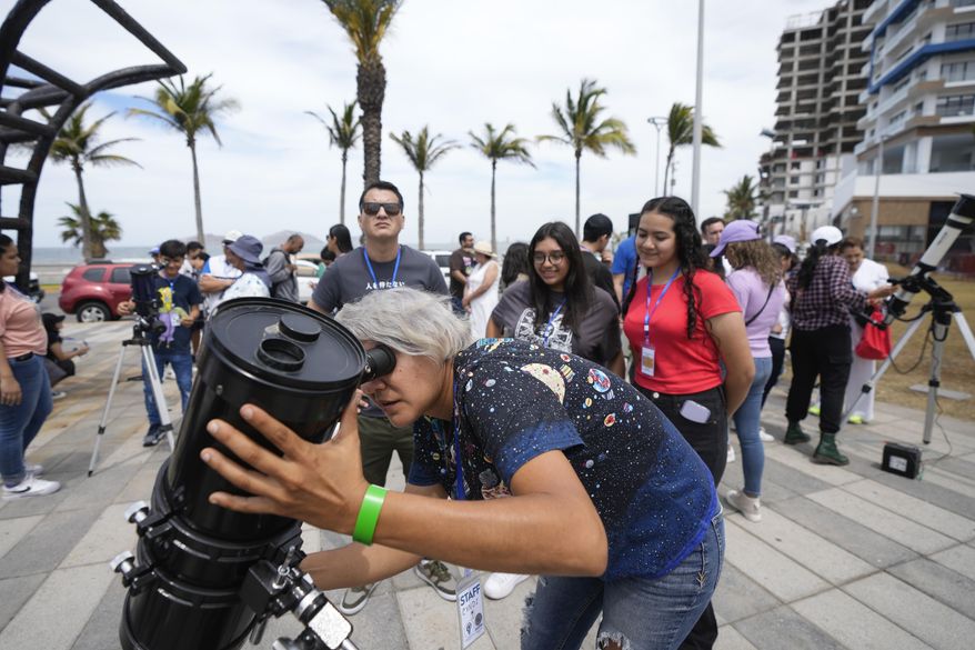 An amateur antronomer prepares her telescophe a day before a total solar eclipse in Mazatlan, Mexico, Sunday, April 7, 2024. (AP Photo/Fernando Llano)