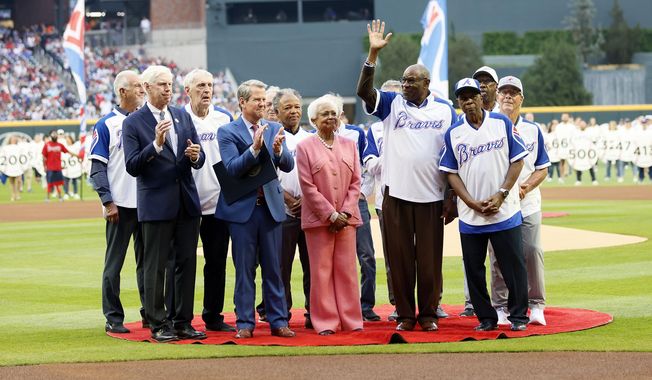 Billye Aaron, center, wife of the late Hank Aaron, stands with Georgia Gov. Brian Kemp, second from front left, Atlanta Braves chairman and CEO Terry McGuirk, front left, Dusty Baker, fourth from right, and players from the 1974 Braves team during a ceremony to mark the 50th anniversary of Hank breaking Babe Ruth&#x27;s home run record team, before a baseball game against the New York Mets, Monday, April 8, 2024, in Atlanta. (Miguel Martinez/Atlanta Journal-Constitution via AP)
