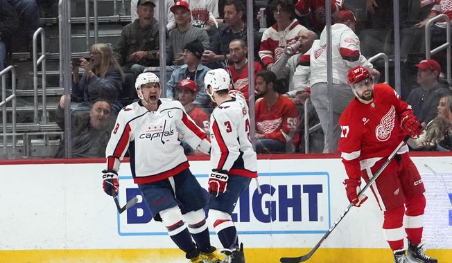 Washington Capitals left wing Alex Ovechkin (8) celebrates his goal with Nick Jensen (3) as Detroit Red Wings left wing David Perron (57) skates away in the second period of an NHL hockey game Tuesday, April 9, 2024, in Detroit. (AP Photo/Paul Sancya)