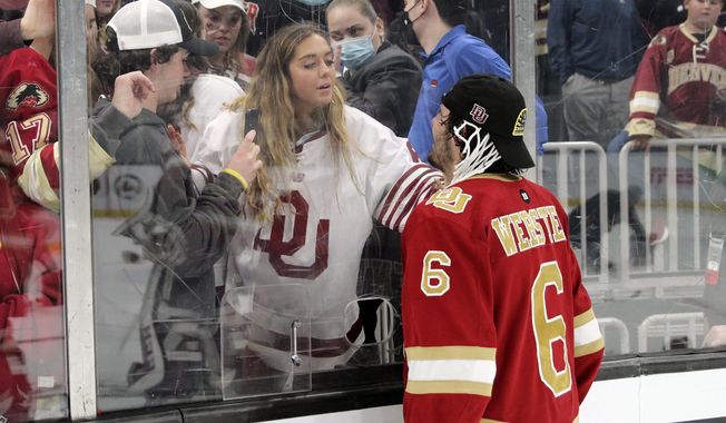 This photo provided by Sunny Hilliard shows Denver Pioneers NCAA college hockey player McKade Webster (6) looking through the glass towards his sister, MaKenna, after Denver beat Minnesota State to win their ninth NCAA national hockey title, in Boston, April 9, 2022. McKade Webster and the Pioneers face Boston University in a 2024 Frozen Four semifinal game, with the winner advancing to the title game. In the Webster family, hockey runs deep. So does winning on the ice. Makenna has now won two NCAA national titles and McKade has one courtesy of the Pioneers&#x27; win in 2022. (Sunny Hilliard via AP)