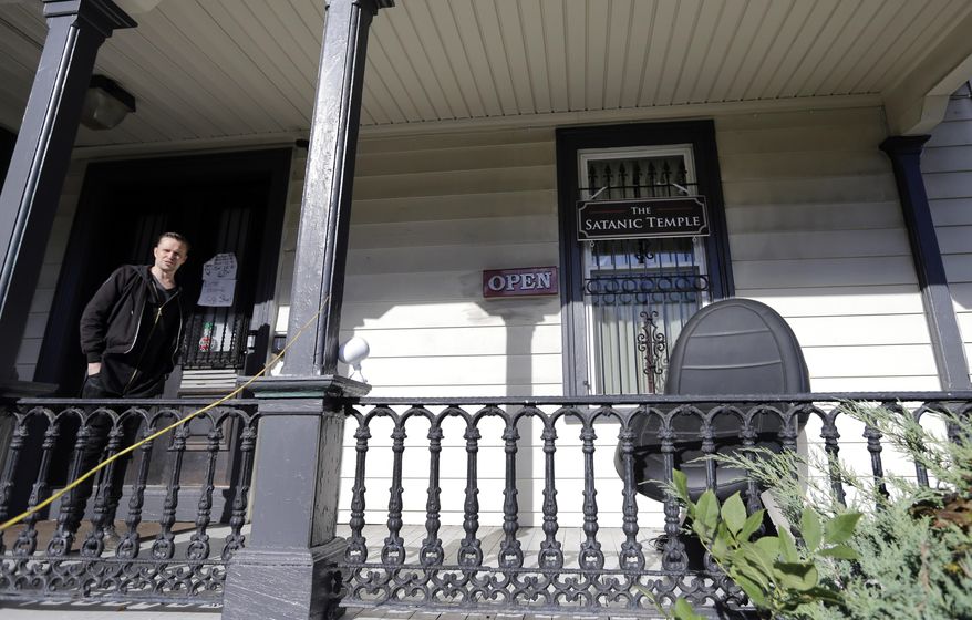 A person stands on the porch of the international headquarters of the Satanic Temple in Salem, Mass., Oct. 24, 2016. Someone threw an explosive device onto the porch of the Satanic Temple in Massachusetts at a time when no one was inside, and the device and damage it caused were not found until nearly 12 hours later, police said. No injuries were reported. State police bomb technicians ensured that the device was no longer a danger, police said in a news release on Monday, April 8, 2024. (AP Photo/Elise Amendola, File)