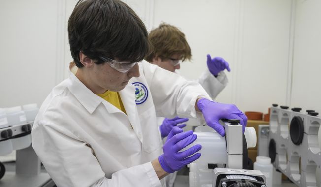 Jackson Quinn, foreground, places a bottle contains a PFAS water sample into a rotator, Wednesday, April 10, 2024, at a U.S. Environmental Protection Agency lab in Cincinnati. The Environmental Protection Agency on Wednesday announced its first-ever limits for several common types of PFAS, the so-called &quot;forever chemicals,&quot; in drinking water. (AP Photo/Joshua A. Bickel)