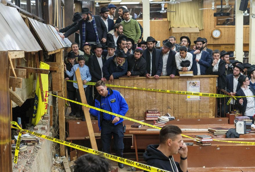FILE - Hasidic Jewish students observe as law enforcement establishes a perimeter around a breached wall in the synagogue that led to a tunnel dug by students, Jan. 8, 2024, in New York. Thirteen members of the Hasidic Jewish community pleaded not guilty Wednesday, April 10, to charges stemming from their alleged role in a dispute over an illegal tunnel built beneath a historic Brooklyn synagogue. (Bruce Schaff via AP, File)