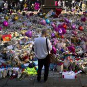 FILE - A man stands next to flowers for the victims of a bombing at St. Ann&#x27;s Square in central Manchester, England, May 26, 2017. More than 250 survivors of the suicide bombing that killed 22 people at a 2017 Ariana Grande concert in Manchester, England, are taking legal action against Britain&#x27;s domestic intelligence agency, lawyers said Sunday, April 14, 2024. (AP Photo/Emilio Morenatti, File)