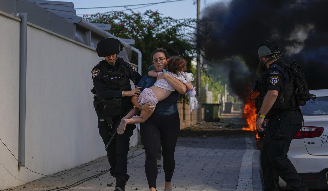 Israeli police officers evacuate a woman and a child from a site hit by a rocket fired from the Gaza Strip, in Ashkelon, southern Israel, Saturday, Oct. 7, 2023. Thousands of Hamas-led militants storm across the border into Israel, killing 1,200 people, mostly civilians, and taking roughly 250 captive, according to Israeli authorities. (AP Photo/Tsafrir Abayov) **FILE**